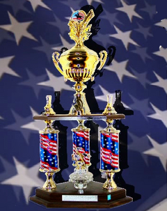 Bild der Pullman City Troophy. Ein goldener Pokal der von drei Seulen in den farben der amerikanischen Flagge getragen wird.